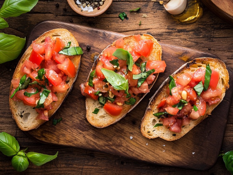 Bruschetta med friske tomater, basilikum og olivenolje på trefjøl