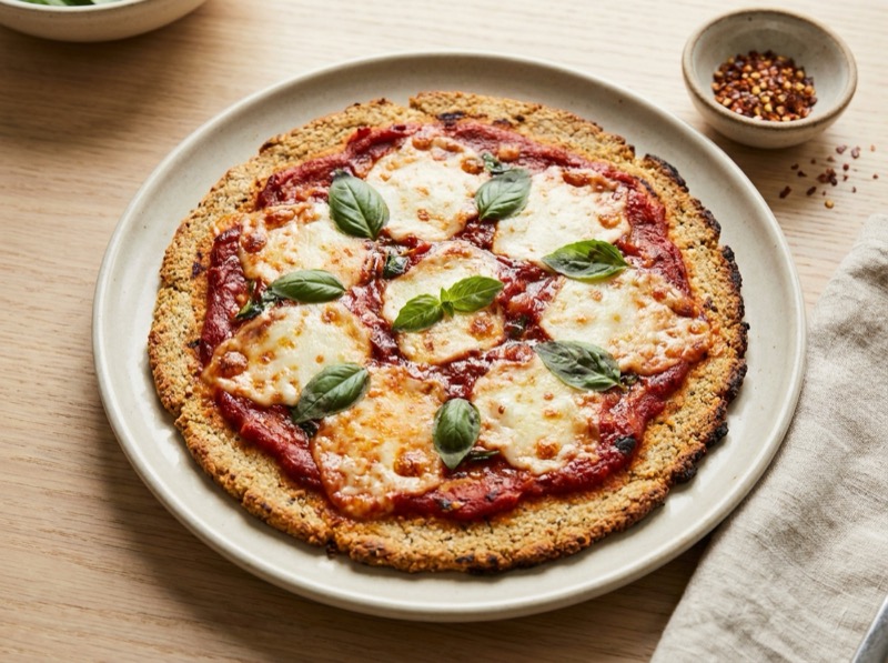 Sprø lavkarbo pizzabunn med mandelmel toppet med tomatsaus og smeltet mozzarella